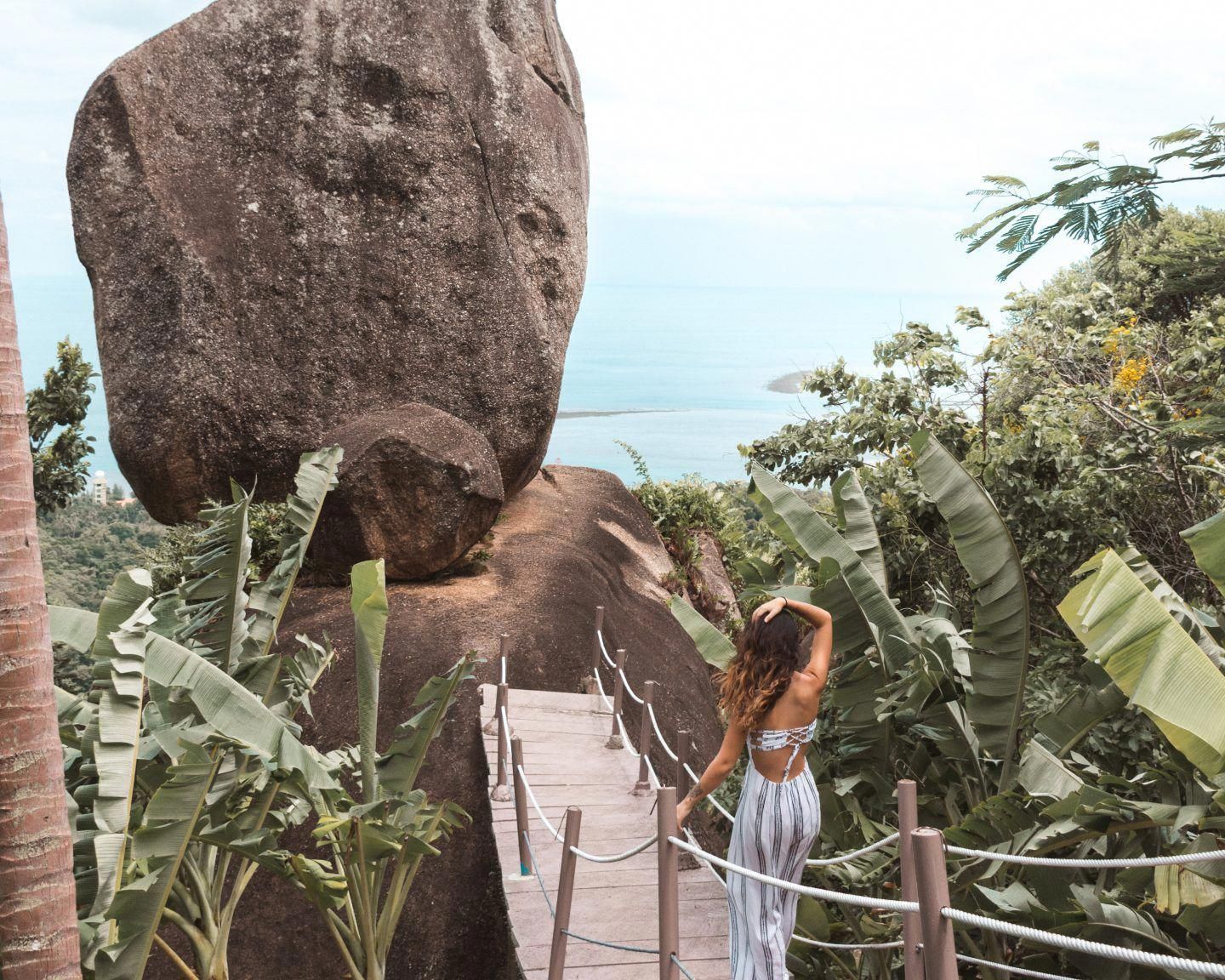 A woman standing on a wooden walkway next to the Overlap Stone in Koh Samui.